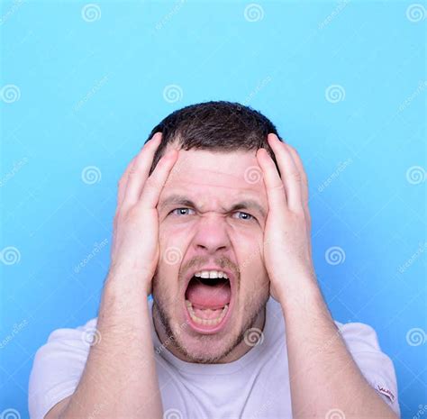 Portrait Of Angry Man Screaming And Pulling Hair Against Blue Ba Stock
