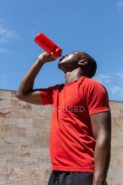 Low Angle Of Thirsty African American Athletic Male Drinking Fresh
