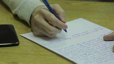 Student Writing On A Piece Of Paper In A Classroom Close Up Stock