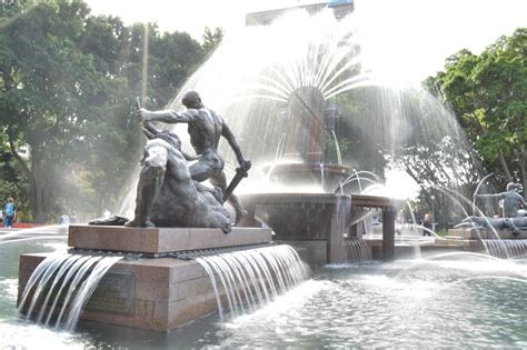 There Is A Fountain With Water Shooting From It And A Statue In The Foreground
