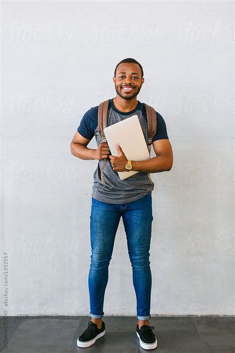 Portrait Of A Black University Man Holding A Laptop In A Library By