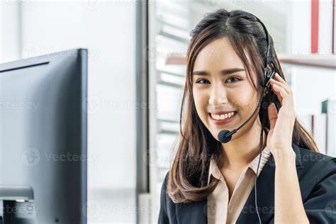 Smiling Friendly Asian Female Call Center Agent With Headset Working On