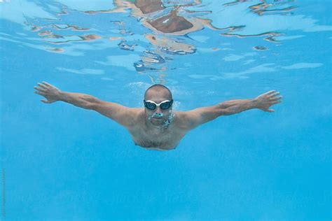 caucasian male with goggles swimming underwater by stocksy contributor ibex media stocksy