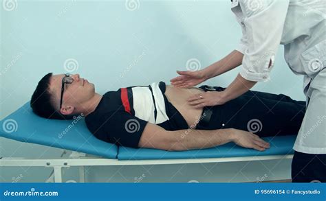 Female Doctor Examining The Abdomen Of Male Patient Lying On The