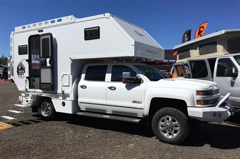 A White Truck With A Camper Attached To It