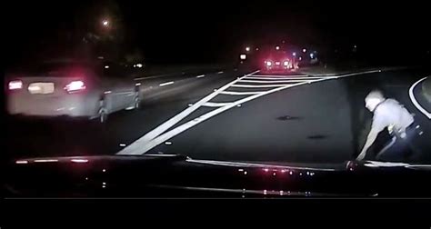 watch cop barely dodges passing car while stopped at crash scene