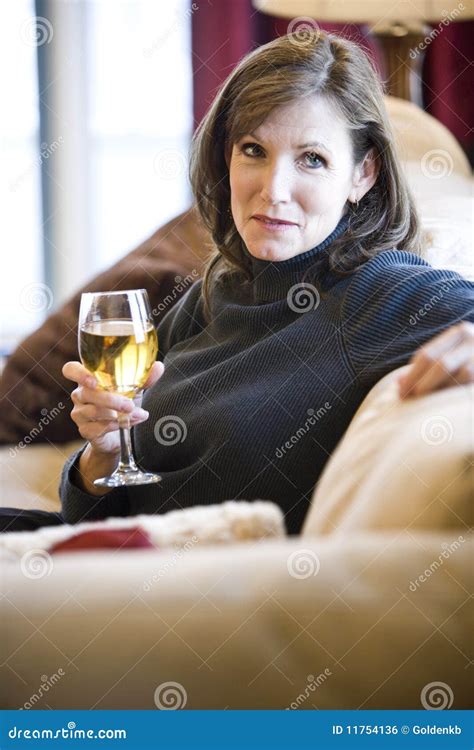 Mulher Madura Que Relaxa No Vinho Bebendo Do Sofá Foto De Stock