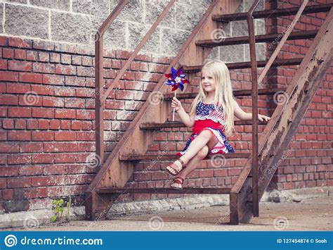 Portrait Of Smiling Little Girl With Pinwheel Sitting On Stairs Stock