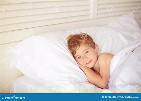 A Boy Quietly Laying In Bed In His Room Putting Hand Under His Head