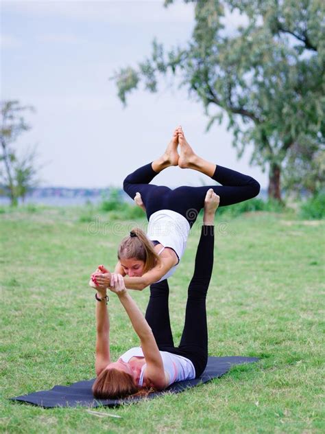 Two Young Happy Beautiful Barefoot Girls Doing Yoga In City Park Contact Yoga Together Stock