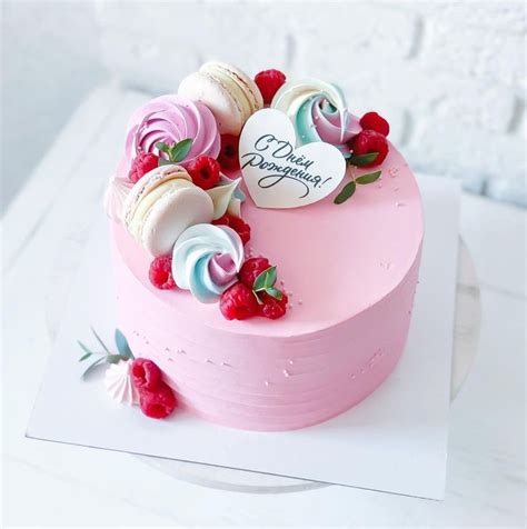 A Pink Cake With White Frosting And Red Raspberries On The Top Is