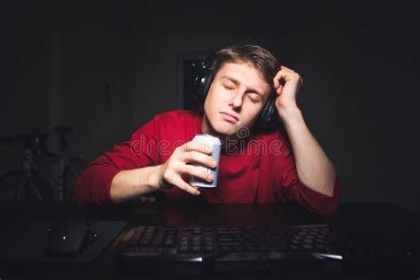 Sleepy Gamer With A Headset Sitting At The Table With A Can Of Drink In