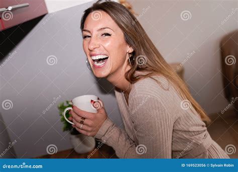 Young Happy Laughing Woman Drinking Coffee On The Kitchen In The