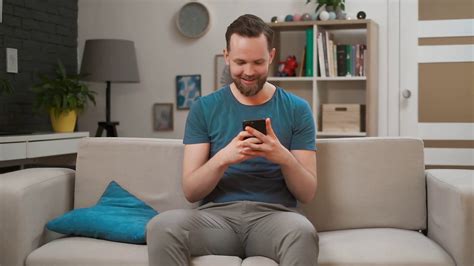 Young Handsome Caucasian Man Using Modern Mobile Smartphone Sitting On