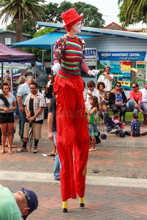 A Male Stilt Walker In Bright Red Clown Garb On The Street Editorial