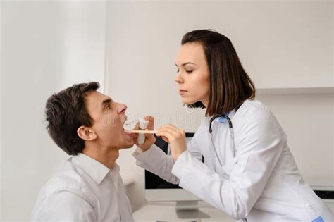 Young Woman Doctor Otolaryngologist Examine Patient Larynx And Oral