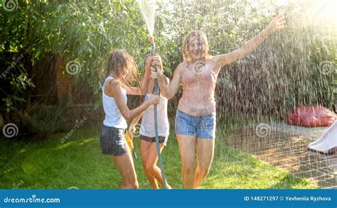 Photo Of Three Cheerful Teenage Girls Dancing In The Backyard Garden Udner Garden Water Hose