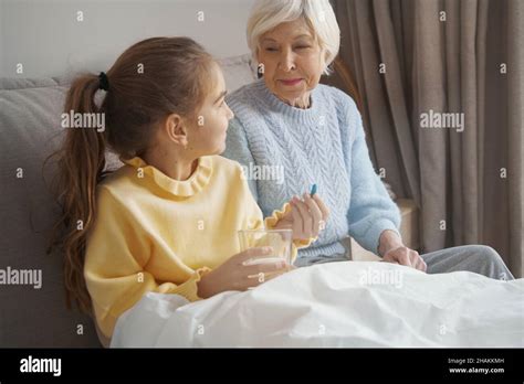 Loving Grandmother Providing Medication For A Sick Little Girl Stock