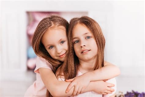 Premium Photo Two Beautiful Girls Sisters Hug Each Other In A Light Room