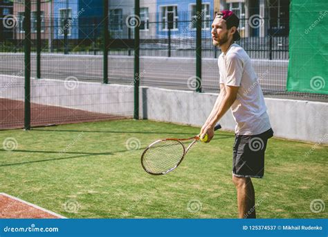 Portrait Of Young Male Tennis Player On Court On A Sunny Day Stock