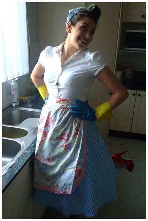A Woman Standing In A Kitchen Next To A Sink Wearing Yellow Gloves And A White Shirt