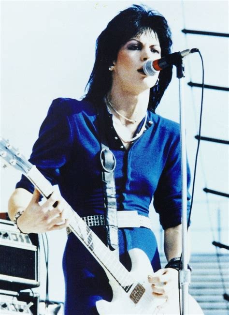 A Woman In Blue Dress Playing An Electric Guitar On Stage With Microphone And Amp Behind Her