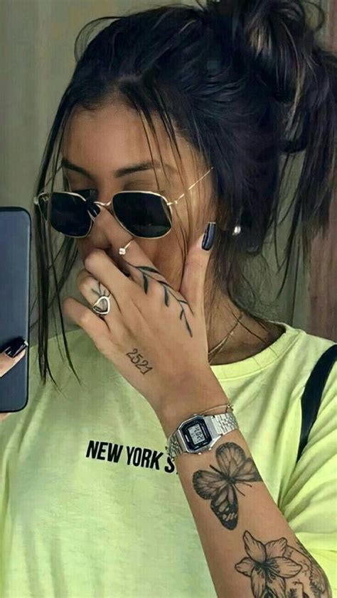 a woman with tattoos on her arm holding a cell phone