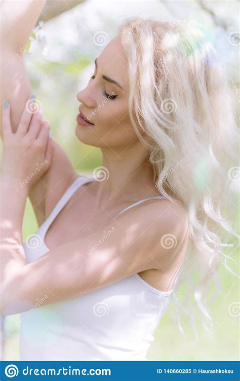 Beautiful Blonde Woman Enjoys In The Blooming Garden Stock Image