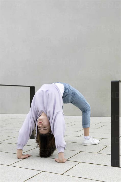 Girl Bending Over Backwards By Wall Stock Photo