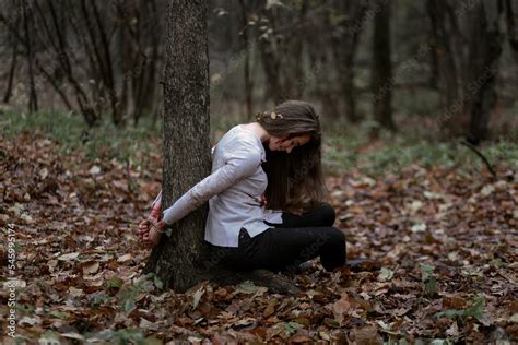 Fotka „unconscious Young Woman Tied To Tree And Sitting On Ground In Dark Forest Girl With