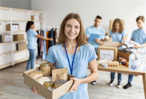 Positive Female Volunteer In Blue Uniform Holding Cardboard Box With