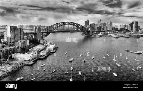 black white image of sydney city cbd landmarks across harbour along sydney harbour bridge with