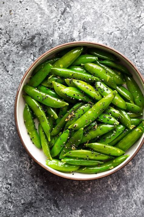 A Bowl Filled With Green Beans And Seasoning On Top Of A Gray Countertop