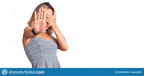 Beautiful Caucasian Woman Wearing Summer Dress Covering Eyes With Hands And Doing Stop Gesture