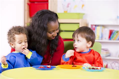 Children Eating Fruit At A Nursery With Their Carer Early Learning