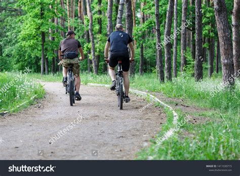 Group of men friends riding bikes in a forest. People ...