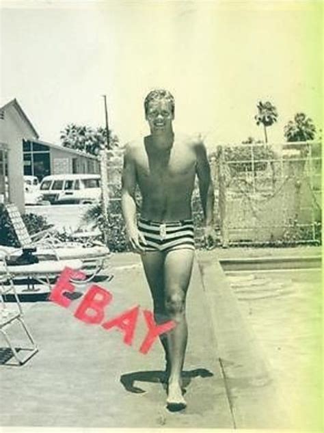 An Old Photo Of A Man In Swim Trunks Walking Down The Sidewalk With His