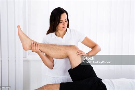 Young Female Masseur Giving Leg Massage To Man Stock Photo Download