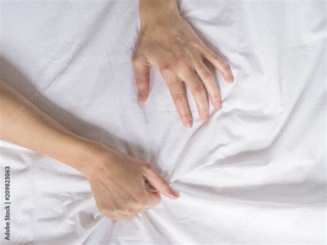 hand clutches grasps a white crumpled bed sheet in a hotel room a sign of ecstasy feeling of