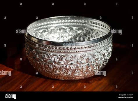 Silver Bowl Resting On Wooden Floor Against A Black Background Stock