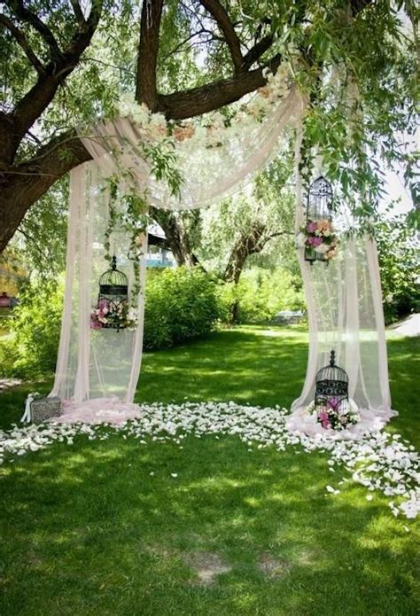 An Outdoor Ceremony Setup With Flowers On The Ground And White Draping