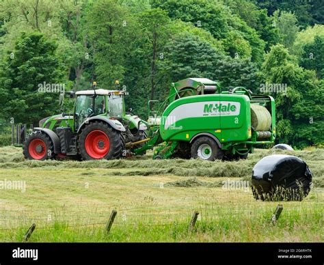 Hay And Silage Making Farmer In Farm Tractor At Work In Rural Field