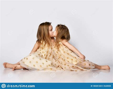 two small beautiful smiling girls sisters in same dresses with stars barefoot sitting on floor