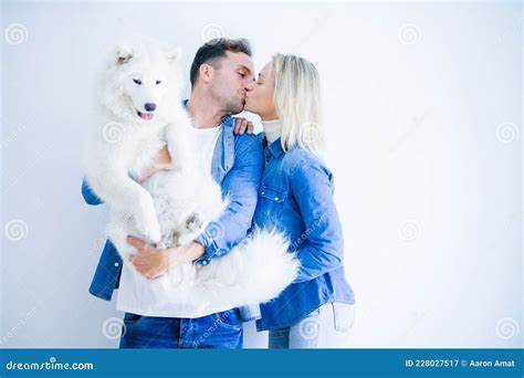 Joven Pareja Hermosa Besando A Perro Parado Sobre Fondo Blanco Aislado Imagen De Archivo
