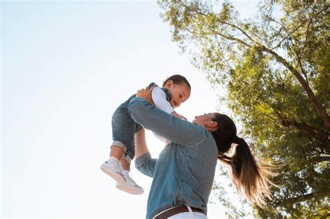Joven Madre Levanta A Su Hijo En Brazos En El Parque Al Atardecer En