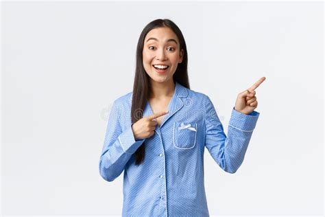 Happy Pleased Asian Girl In Blue Pajamas At Sleepover Party Pointing