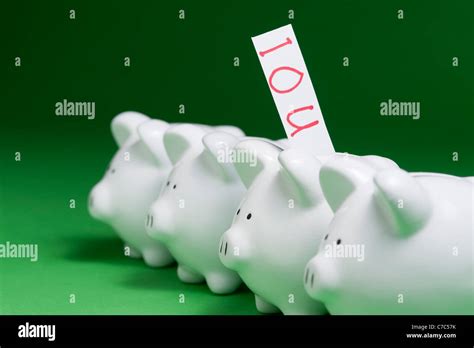 Group Of Piggy Banks With Ious Coming Out Of Coin Slots Stock Photo