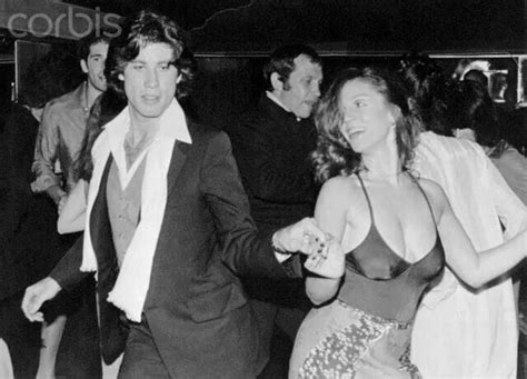 black and white photograph of two people dancing at a party with other people in the background