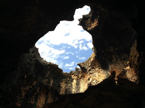 The Sky Is Shining Through An Opening In A Rock Formation With Clouds