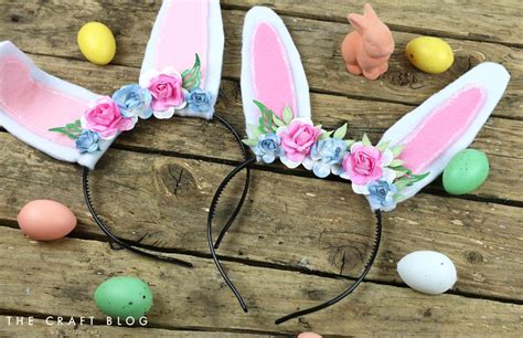 An Easter Bunny Ears Headband With Flowers And Eggs Around It On A